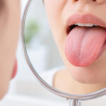 鏡を見ながら舌を出して色や表面の状態を確認しているイメージ
